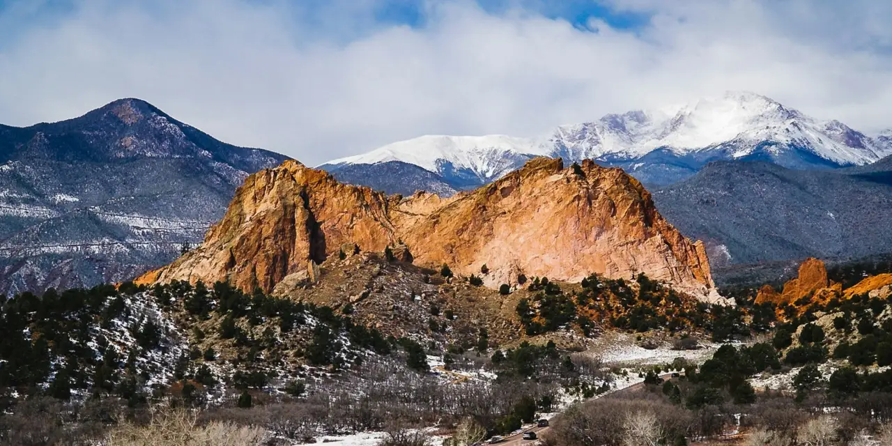 Red rock formations of the Garden of the Gods with snow-capped mountains behind
